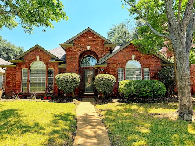 traditional-style house with brick siding, a shingled roof, and a front yard