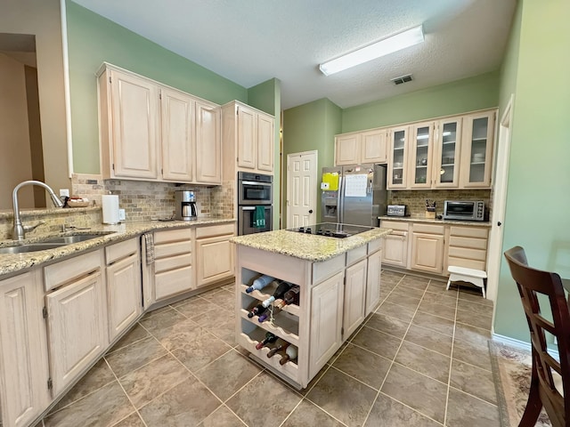 kitchen with a kitchen island, a toaster, light stone counters, stainless steel appliances, and a sink