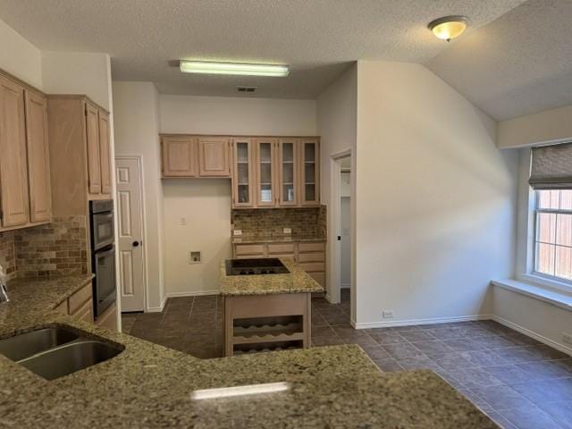 kitchen with black appliances, a sink, decorative backsplash, light stone countertops, and vaulted ceiling