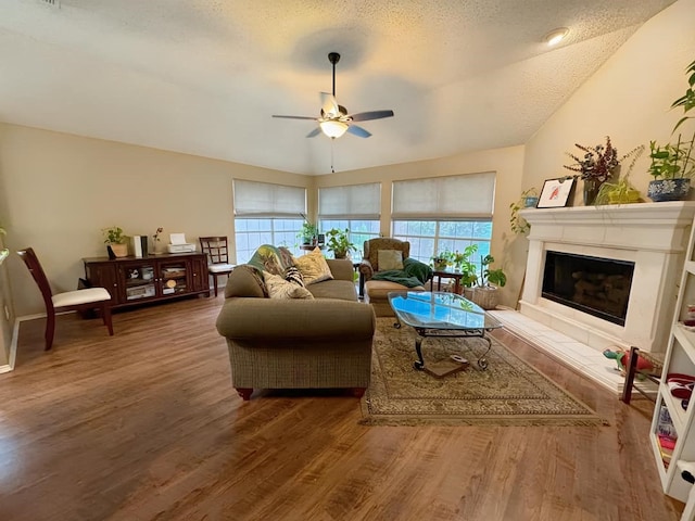 living area with a glass covered fireplace, plenty of natural light, and wood finished floors