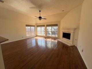 unfurnished living room with a fireplace with raised hearth, a healthy amount of sunlight, a ceiling fan, and wood finished floors