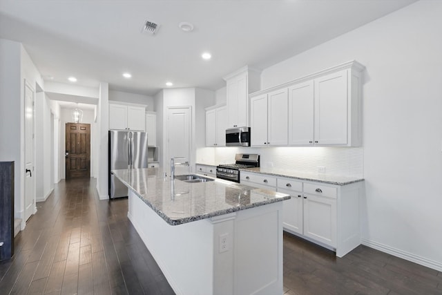 kitchen featuring visible vents, a kitchen island with sink, stainless steel appliances, white cabinetry, and a sink