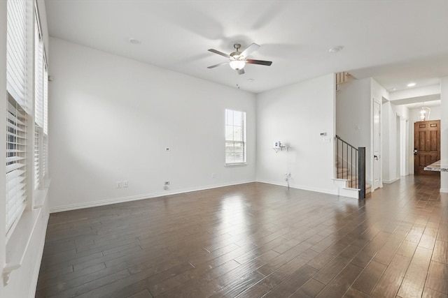 interior space featuring baseboards, stairway, ceiling fan, and dark wood-style flooring