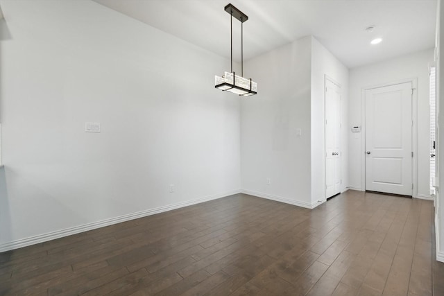 unfurnished dining area featuring dark wood-style floors, recessed lighting, a notable chandelier, and baseboards