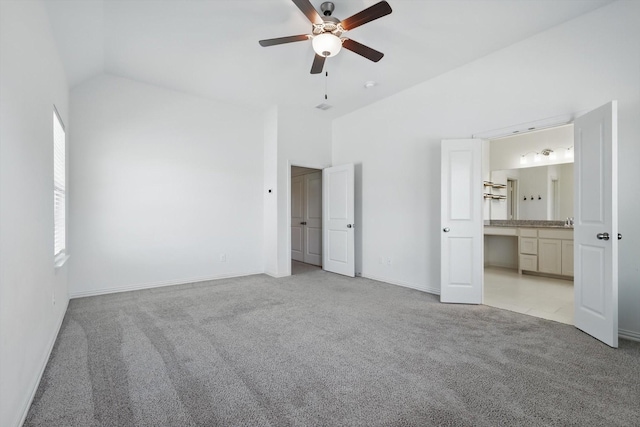 unfurnished bedroom with lofted ceiling, light colored carpet, connected bathroom, ceiling fan, and baseboards