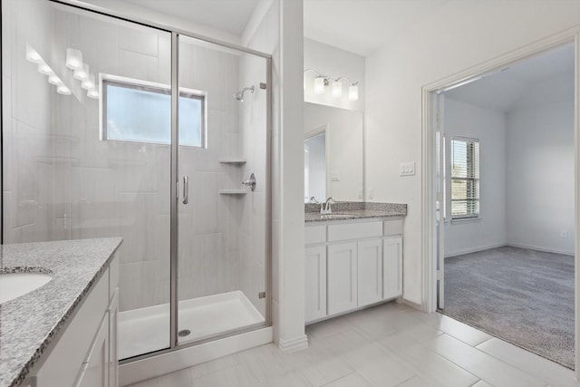 full bath featuring a stall shower, tile patterned flooring, vanity, and baseboards