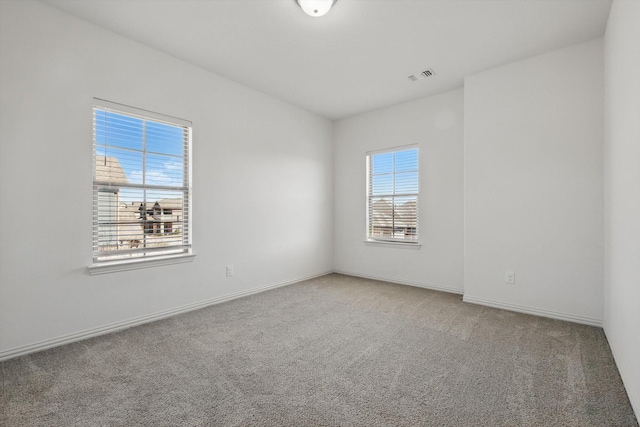 spare room featuring carpet, visible vents, and baseboards