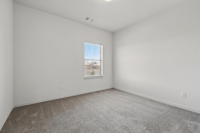 carpeted spare room with visible vents and baseboards