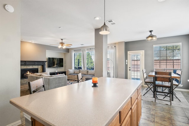 kitchen featuring a kitchen island, visible vents, baseboards, light countertops, and a tiled fireplace