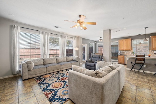 living area with ceiling fan, visible vents, and baseboards