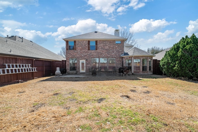 back of property featuring brick siding, a patio, a chimney, a lawn, and fence