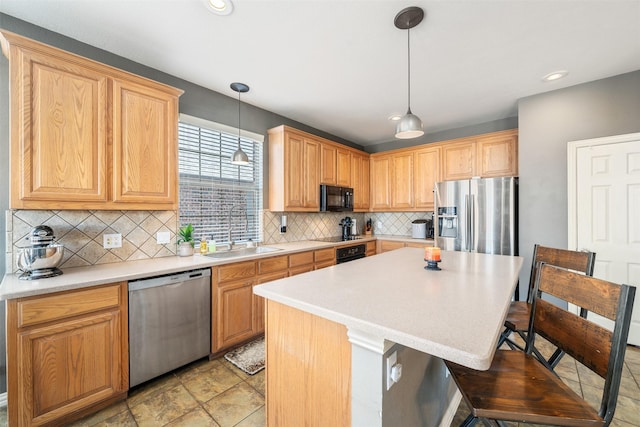 kitchen with decorative backsplash, a breakfast bar area, appliances with stainless steel finishes, pendant lighting, and a sink