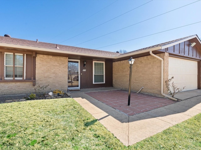 view of front facade with an attached garage, a patio area, a front yard, and brick siding