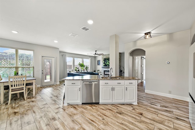 kitchen featuring arched walkways, visible vents, wood tiled floor, dark stone counters, and dishwasher