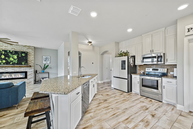 kitchen featuring stainless steel appliances, a sink, visible vents, open floor plan, and tasteful backsplash