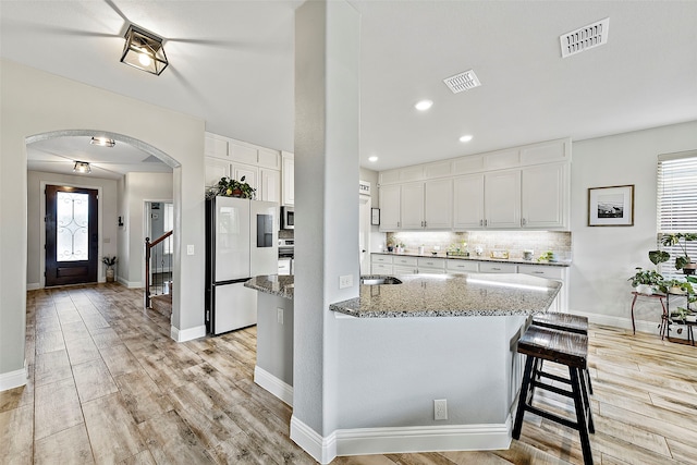 kitchen featuring tasteful backsplash, arched walkways, visible vents, and smart refrigerator