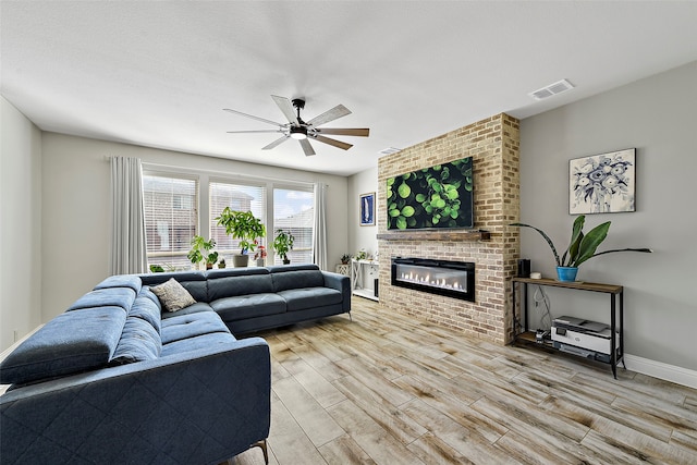 living area with light wood finished floors, visible vents, a brick fireplace, ceiling fan, and baseboards