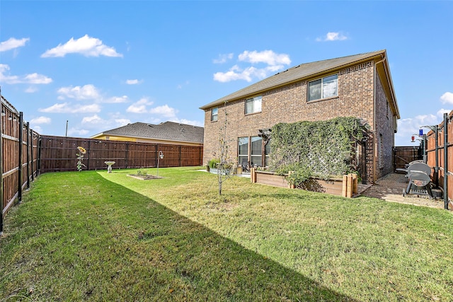 back of house with brick siding, a lawn, a fenced backyard, and a garden