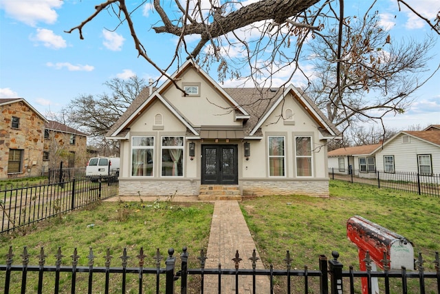 view of front of property featuring a fenced front yard, stone siding, french doors, roof with shingles, and a front yard