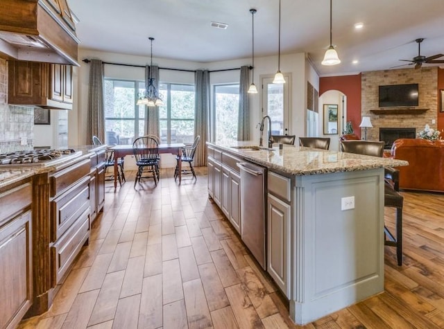 kitchen with a breakfast bar, open floor plan, stainless steel dishwasher, light wood-style floors, and a sink