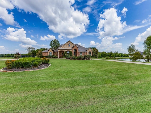 french country home featuring brick siding and a front lawn