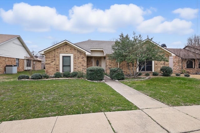 ranch-style home featuring brick siding, roof with shingles, a front lawn, and central AC unit