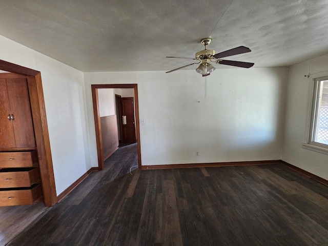 spare room with a textured ceiling, dark wood finished floors, a ceiling fan, and baseboards