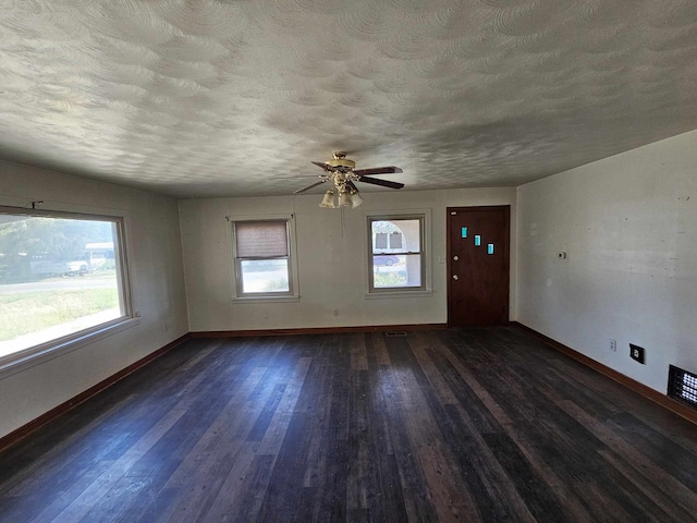 interior space featuring a healthy amount of sunlight, a textured ceiling, baseboards, and wood finished floors