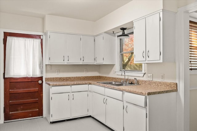 kitchen with white cabinets, light countertops, and a sink