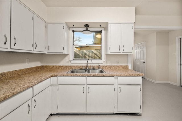 kitchen with light countertops, a sink, white cabinetry, and baseboards