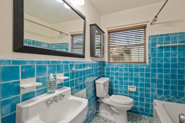 full bath with wainscoting, a sink, tile walls, and toilet