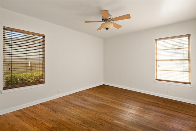 empty room featuring a ceiling fan, baseboards, a wealth of natural light, and wood finished floors