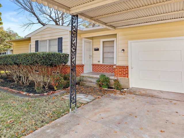 property entrance featuring a garage, driveway, and brick siding