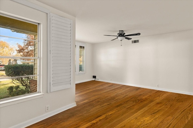 unfurnished room with a wealth of natural light, visible vents, baseboards, and wood finished floors