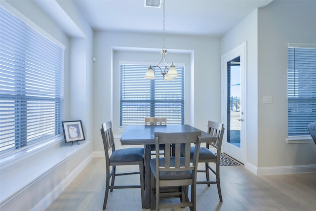 dining area with an inviting chandelier, visible vents, baseboards, and wood finished floors