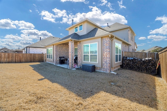 back of house with a patio area, a fenced backyard, a shingled roof, and brick siding