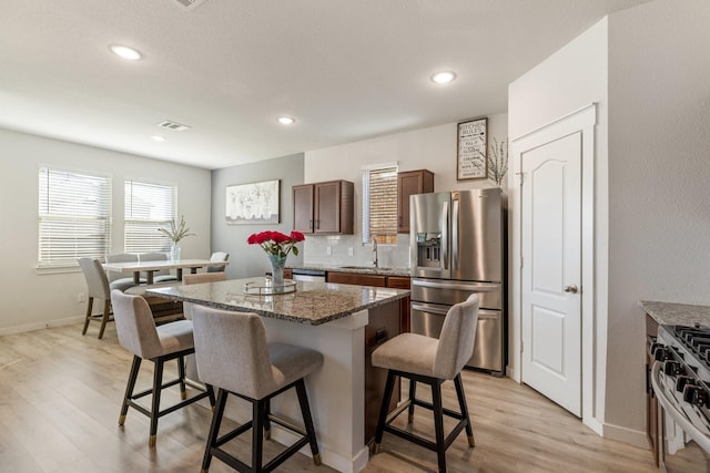 kitchen featuring stainless steel appliances, a breakfast bar, a center island, and a sink