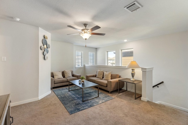 carpeted living area with baseboards, visible vents, ceiling fan, and a textured ceiling