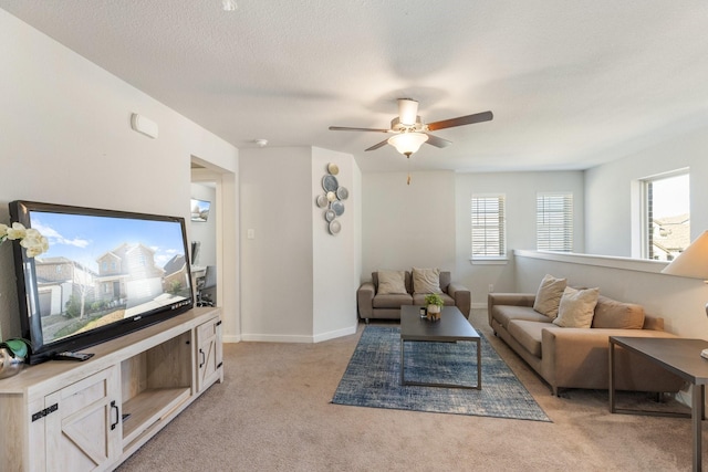 living area featuring a ceiling fan, baseboards, a textured ceiling, and light colored carpet