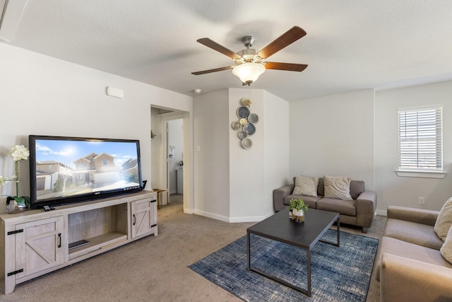 living room featuring light carpet, ceiling fan, a textured ceiling, and baseboards