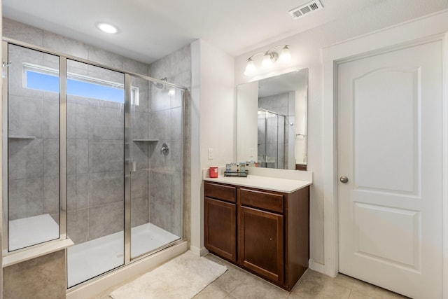 bathroom with a stall shower, vanity, visible vents, and tile patterned floors