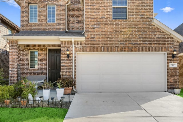 view of front facade with fence, concrete driveway, and brick siding