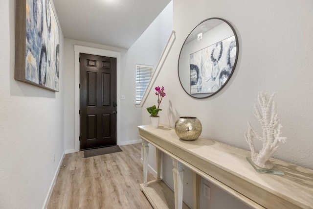 foyer with light wood-style floors and baseboards