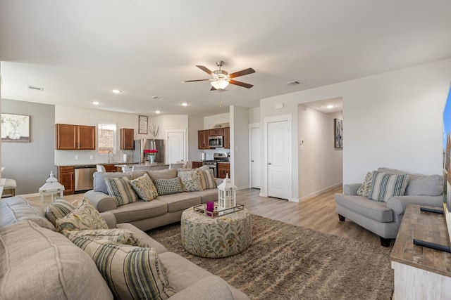 living area with light wood-style flooring, visible vents, baseboards, and recessed lighting