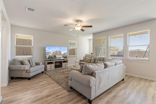 living area with a ceiling fan, light wood-style flooring, visible vents, and baseboards