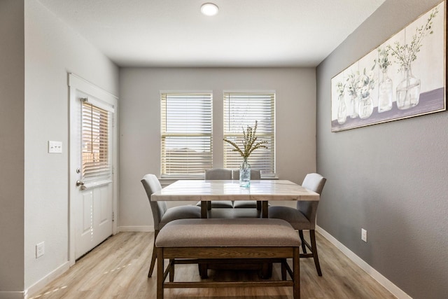 dining area with baseboards and light wood finished floors