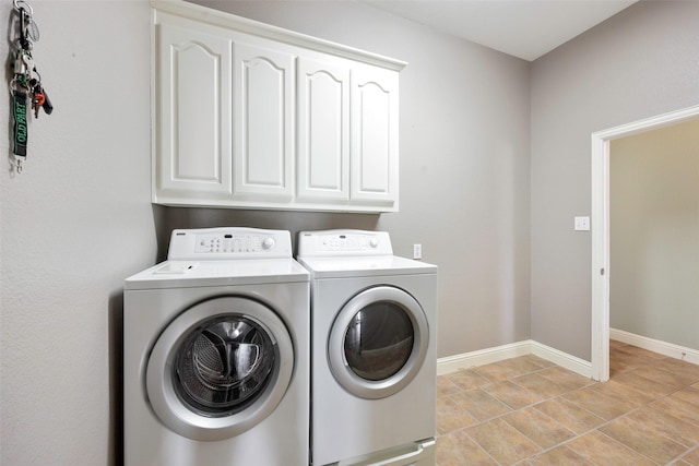 clothes washing area featuring cabinet space, washing machine and dryer, and baseboards