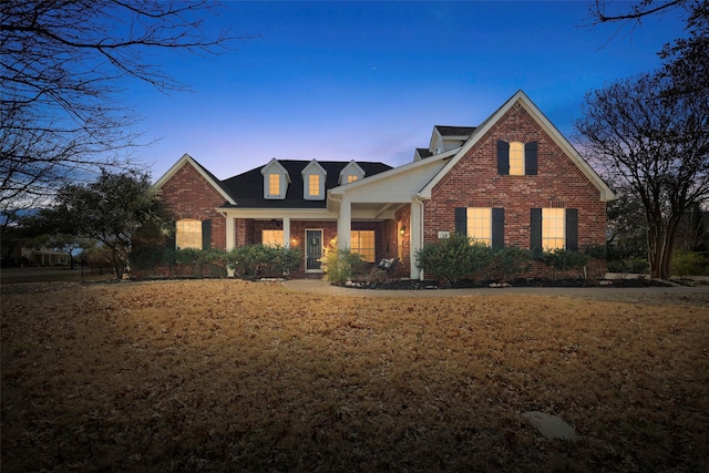 view of front facade with brick siding and a front lawn