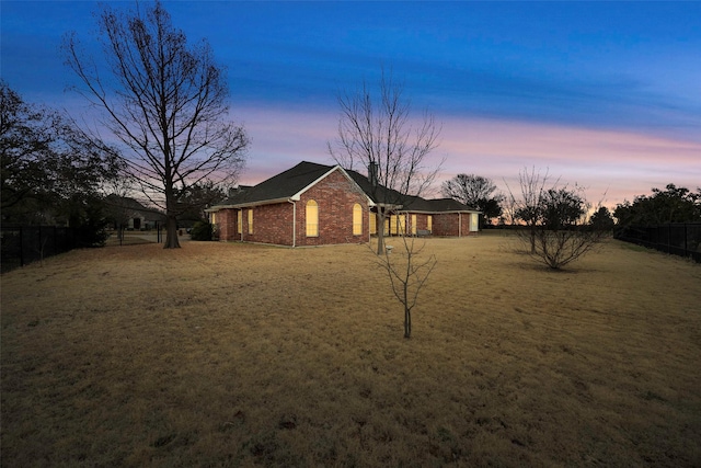 exterior space featuring a yard, brick siding, and fence