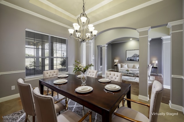 dining area featuring arched walkways, baseboards, ornamental molding, a tray ceiling, and decorative columns